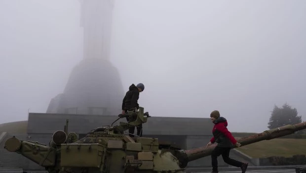 Niños juegan en un tanque instalado como monumento en Kiev, Ucrania, frente al monumento a la Madre Patria, reabierto recientemente al público. (21 de octubre de 2023)