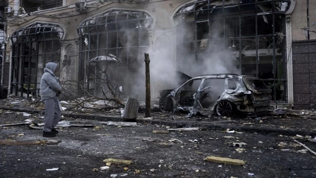 Una mujer sostiene a su perro mientras camina frente a un automóvil destruido en llamas después de un ataque ruso en Kiev, Ucrania (20-12-2024)