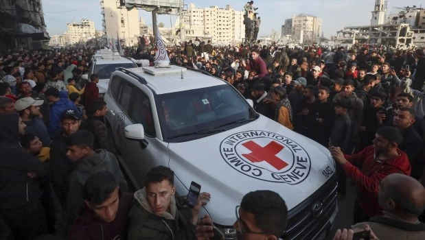 Las tres mujeres en los vehículos de la Cruz Roja en la Ciudad de Gaza, rodeadas por una multitud que creció hasta los miles mientras las personas levantaban teléfonos móviles y se subían a los coches.