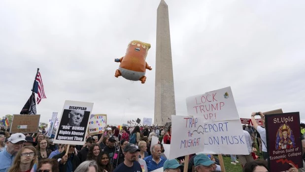 Manifestantes portan pancartas durante las protestas de "¡Manos Fuera!" contra Donald Trump en el Monumento a Washington.