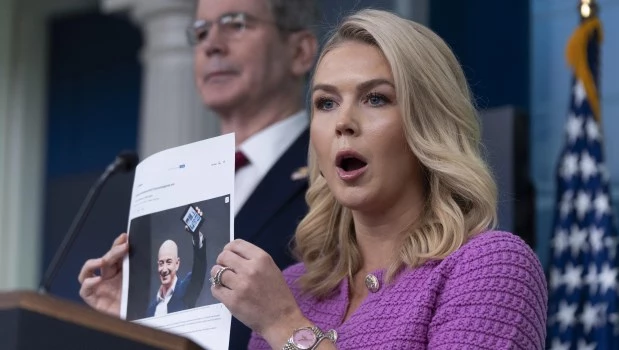 La secretaria de prensa de la Casa Blanca, Karoline Leavitt, junto al secretario del Tesoro, Scott Bessent, atrás a la izquierda, muestra una foto de Jeff Besos mientras responde a una pregunta sobre Amazon, durante una rueda de prensa.