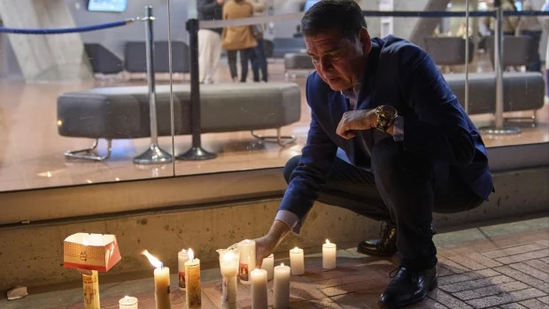 Un hombre enciende velas afuera de la clínica donde el senador colombiano Miguel Uribe Turbay recibe atención médica.