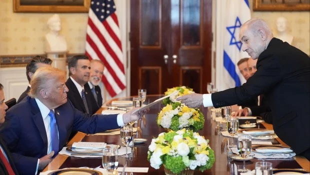 El primer ministro israelí Benjamin Netanyahu le entrega al presidente Donald Trump una carpeta durante una reunión en el Salón Azul de la Casa Blanca.