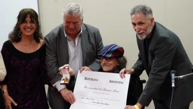 Asoma Charly García detrás del diploma que acredita su Doctorado.