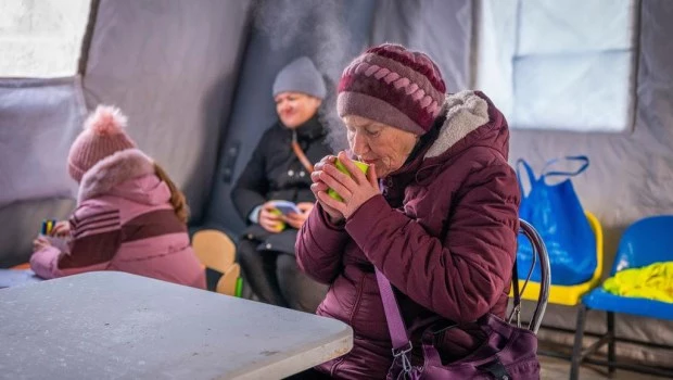 Una mujer se calienta con una taza de té en un centro de emergencia creado para ayudar a las personas durante los cortes de energía causados por los ataques aéreos regulares de Rusia contra la infraestructura energética del país, en Boryspil, Ucrania.