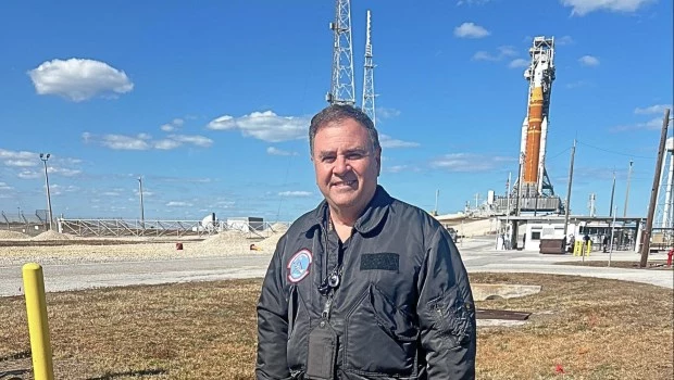 El ingeniero Pablo de León posa junto al colosal cohete SLS de la misión Artemis II que utiliza hardware de transbordadores.