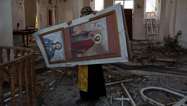 Un capellán militar limpia de escombros un icono antes de la misa del Domingo de Ramos en una iglesia ortodoxa dañada por las tropas rusas en la ciudad de Orikhiv, en la región de Zaporizhzhia, Ucrania (5 de abril de 2026)