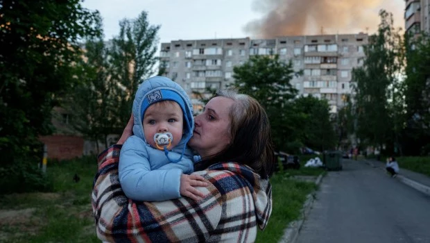 Una mujer lleva a un bebé en brazos cerca de una vivienda dañada tras un ataque ruso en Kiev, Ucrania (2-6-2026).