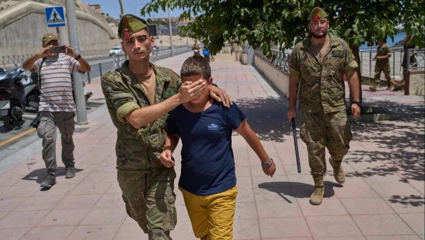 Un niño de 12 años, sin sus padres, es escoltado por un soldado español hacia la frontera.