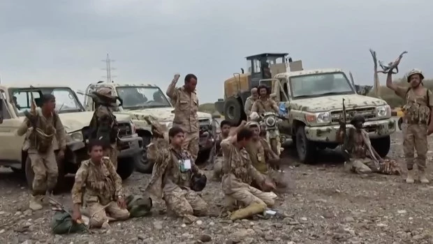 Combatientes hutíes cantan luego de rezar junto a vehículos militares, en medio de sus avances territoriales.